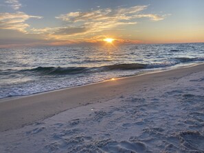 Una playa con olas y un atardecer.