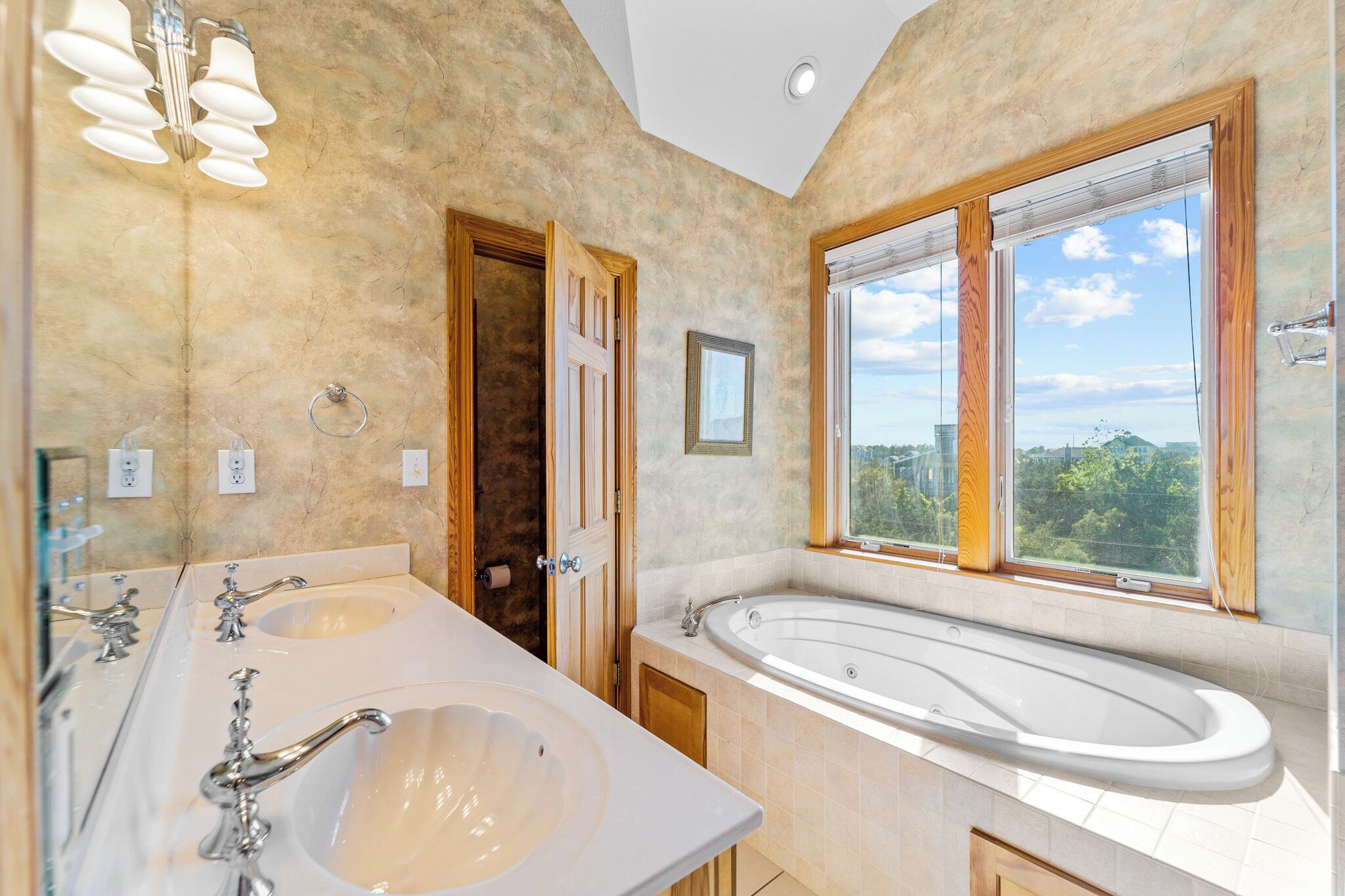 Une salle de bain avec deux lavabos, une baignoire et une grande fenêtre donnant sur un paysage agréable.