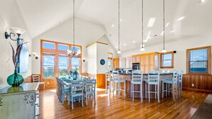 Una cocina amplia con gabinetes de madera, una isla central con taburetes de bar e iluminación colgante.