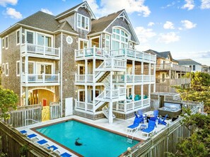 A multi-story house with a pool, balconies, and a wooden deck.
