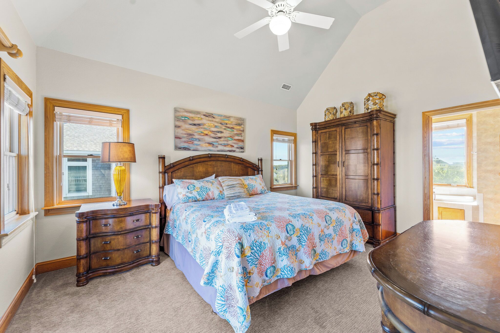 A bedroom with a bed, a nightstand, a dresser, a ceiling fan, and a window with blinds.