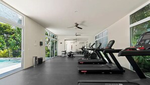 A gym with treadmills, exercise balls, and a pool visible through large windows.