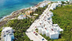 An aerial view of a coastal resort with white buildings, a beach, and clear blue waters.