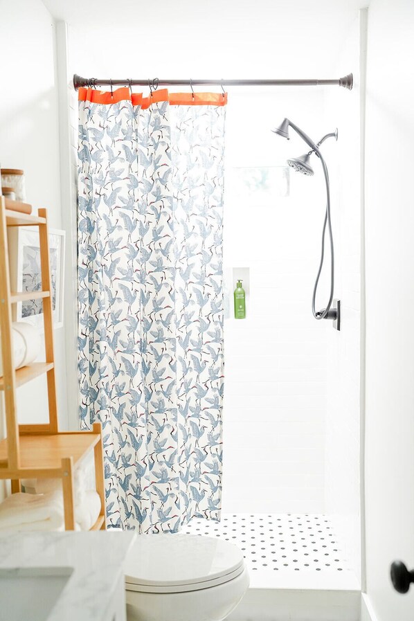 A bathroom with a shower curtain featuring a bird pattern, a toilet, and a sink.