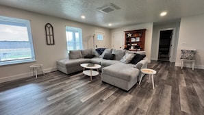 A modern living room with a sectional sofa, two small side tables, and a bookshelf. - Close to everything-tucked away from the noise. A brand-new, blissful stay. (Ithaca)