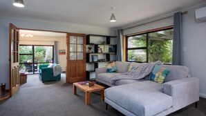 A modern living room with a grey sofa, wooden coffee table, and a bookshelf. - Comfort, Style, Relaxation. Your Home Away from Home Awaits! (Blenheim)