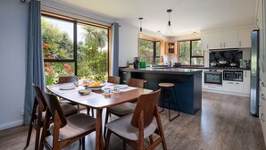 A modern kitchen with a central island, wooden dining table, and chairs. - Comfort, Style, Relaxation. Your Home Away from Home Awaits! (Blenheim)