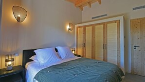 Un dormitorio con cama, dos lámparas de noche, un armario y techo de madera.