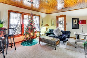 Una sala de estar acogedora con techo de madera, un árbol de Navidad, un sofá, una mesa de centro y una lámpara.