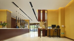 Un moderno vestíbulo de hotel con recepción, zona de bar y espacio para sentarse.