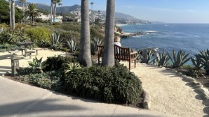 A coastal garden with palm trees, a wooden bench, and a view of the ocean. - 1-Bd 1-Bth Apt, Disney & Anaheim Conv Ctr in 10 Mins! Full Kitchen & Outdr Space (Santa Ana)