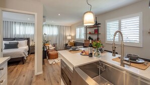 A modern hotel room with a large bed, a separate sitting area, a kitchenette, and a bathroom. - 1-Bd 1-Bth Apt, Disney & Anaheim Conv Ctr in 10 Mins! Full Kitchen & Outdr Space (Santa Ana)