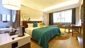 Una habitación de hotel con cama, escritorio, silla, lámpara, lavamanos y ventana.