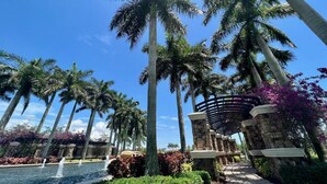A resort with palm trees, a pool, and a stone structure. - Luxurious Family Home - Spacious Kitchen & BBQ (Pompano Beach)