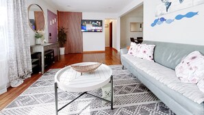 A living room with a sofa, a coffee table, a TV, and a world map on the wall. - Comfy 3Bedrooms 2Bathrooms Excellent Location Home near to Downtown Pittsburgh (Pittsburgh)