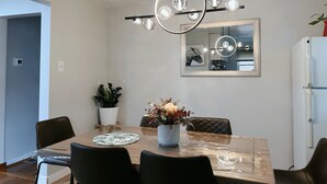 A modern dining area with a wooden table, black chairs, a central vase with flowers, a pendant light, and a large mirror on the wall. - Comfy 3Bedrooms 2Bathrooms Excellent Location Home near to Downtown Pittsburgh (Pittsburgh)