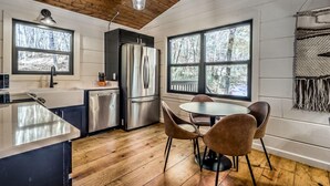 Une cuisine moderne équipée d’un réfrigérateur en acier inoxydable, d’un lave-vaisselle et d’une table à manger en bois avec quatre chaises.