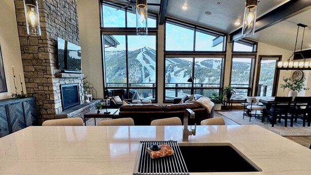 A spacious kitchen with a large island, stone walls, and large windows offering a mountain view. - Winterfell at Winter Park Resort, New Luxury Home | Private Hot Tub | Stunning Views (Winter Park)