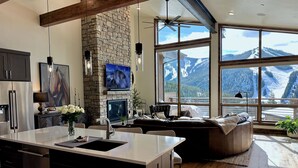 A modern kitchen with a stone wall, large windows with mountain views, and a cozy seating area. - Winterfell at Winter Park Resort, New Luxury Home | Private Hot Tub | Stunning Views (Winter Park)