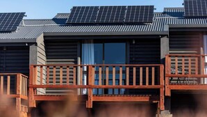 Een chalet met een houten terras en zonnepanelen op het dak.