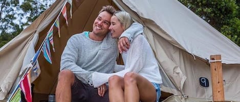A couple sitting on wooden steps outside a tent with a number '9' sign.