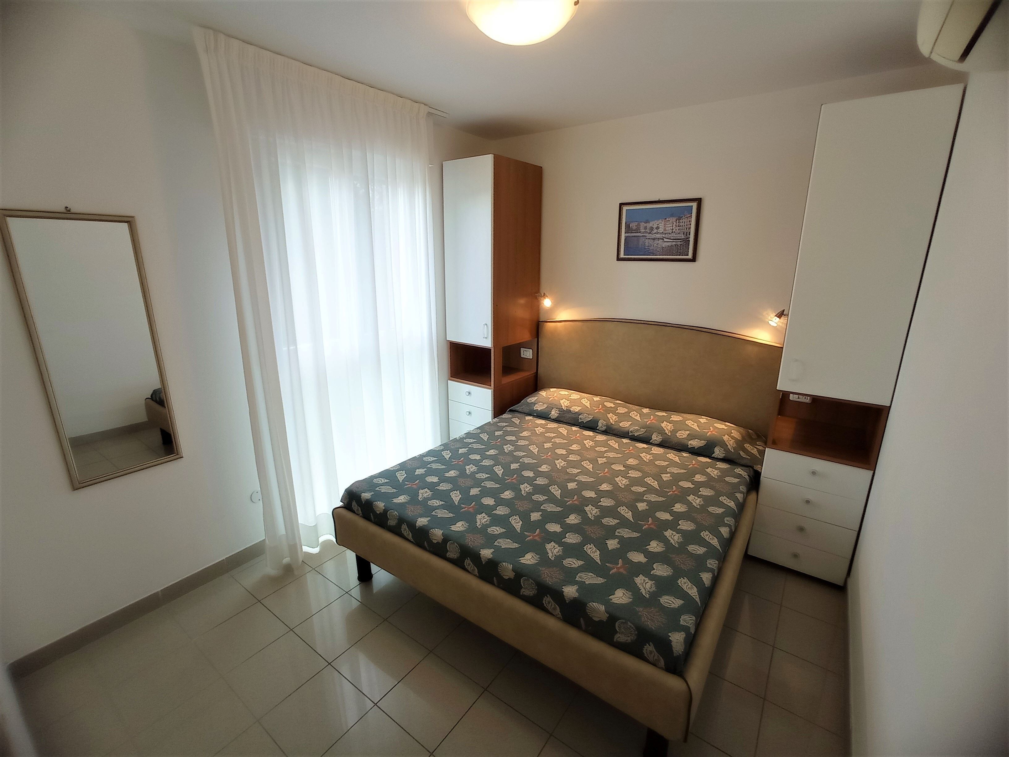 Una camera da letto con un letto, un armadio, uno specchio e un quadro appeso alla parete.