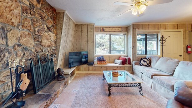 A cozy living room with a stone fireplace, a television, a sofa, and a coffee table. - Close to Lifts | WIFI | Easy Access | Pinetree 318 (Angel Fire)