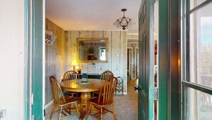 A dining area with a round wooden table, four chairs, a chandelier, and a large mirror on the wall. - Close to Lifts | WIFI | Easy Access | Pinetree 318 (Angel Fire)