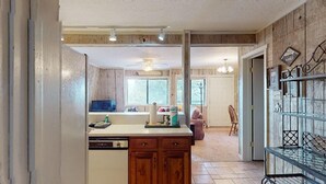 A kitchen with wooden cabinets, a central island, and a dining area with a chair and table. - Close to Lifts | WIFI | Easy Access | Pinetree 318 (Angel Fire)