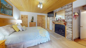 A bedroom with a bed, wooden wardrobe, fireplace, and a painting on the wall. - Close to Lifts | WIFI | Easy Access | Angel Fire Chalet 5 (Angel Fire)