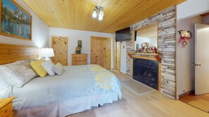 Une chambre à coucher avec un lit, une armoire en bois, une cheminée et un tableau au mur.