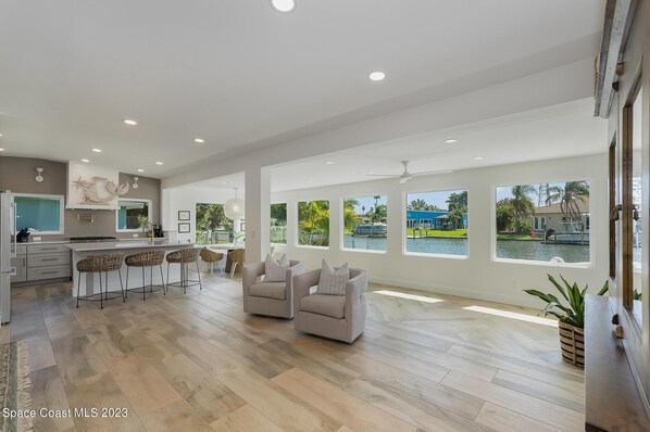 A spacious kitchen with a bar area, large windows, and a view of a water body.