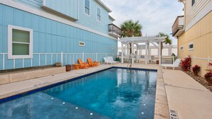 A swimming pool with lounge chairs and a pergola. - Free Sail in Port Aransas! (Port Aransas)