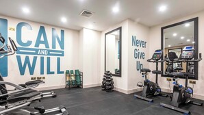 Une salle de sport avec des œuvres d’art motivantes sur les murs, du matériel d’exercice et un miroir.