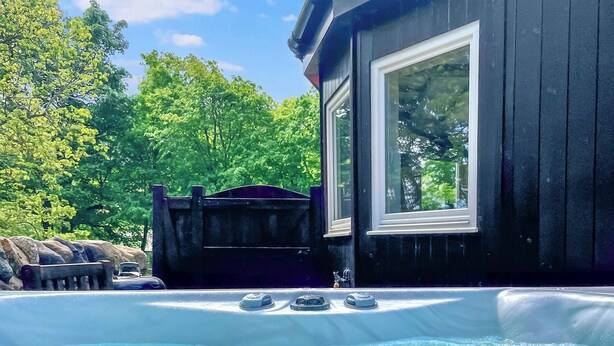 Un jacuzzi con vista a un edificio de madera y árboles.