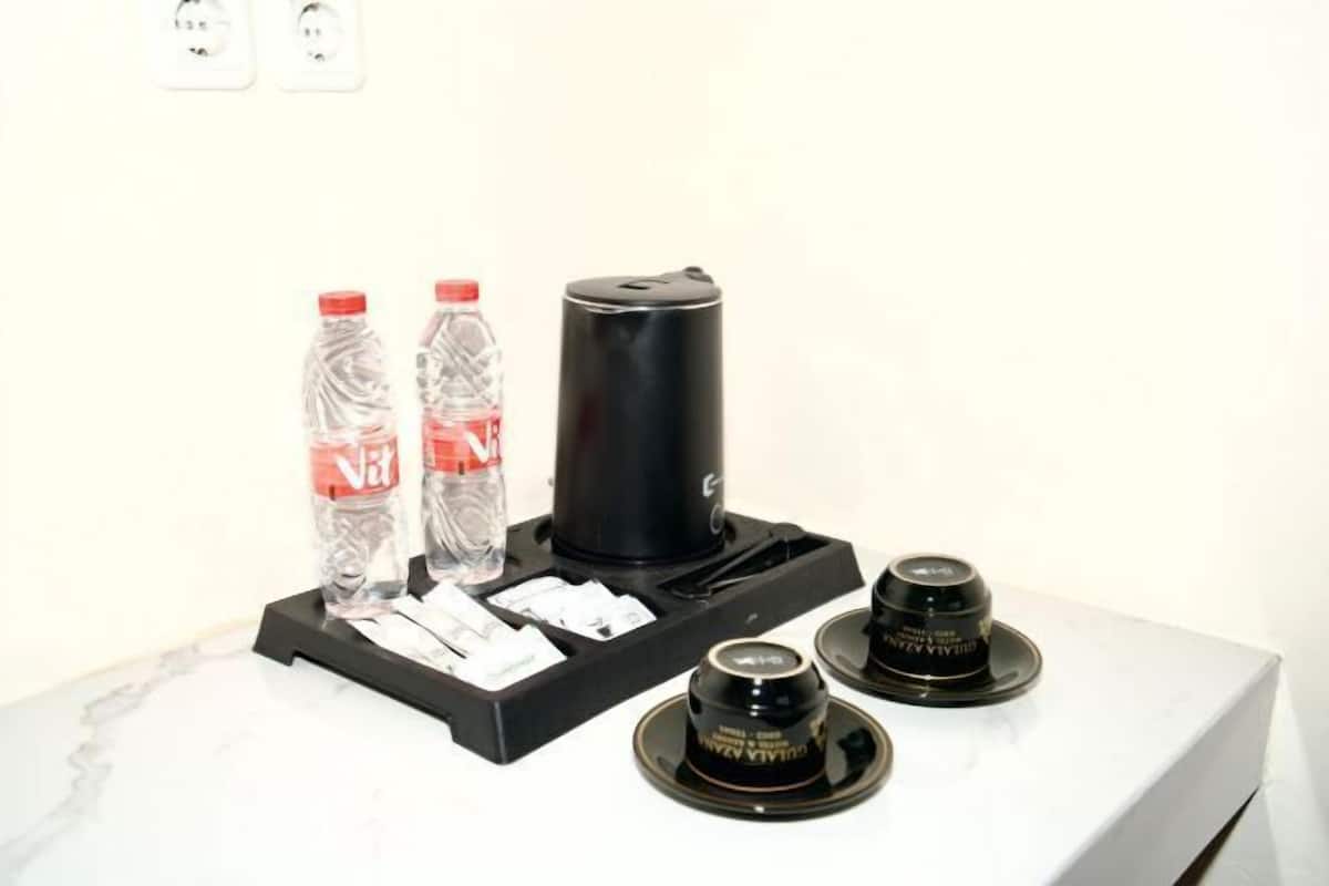 A coffee maker, two water bottles, and a small container on a white surface.