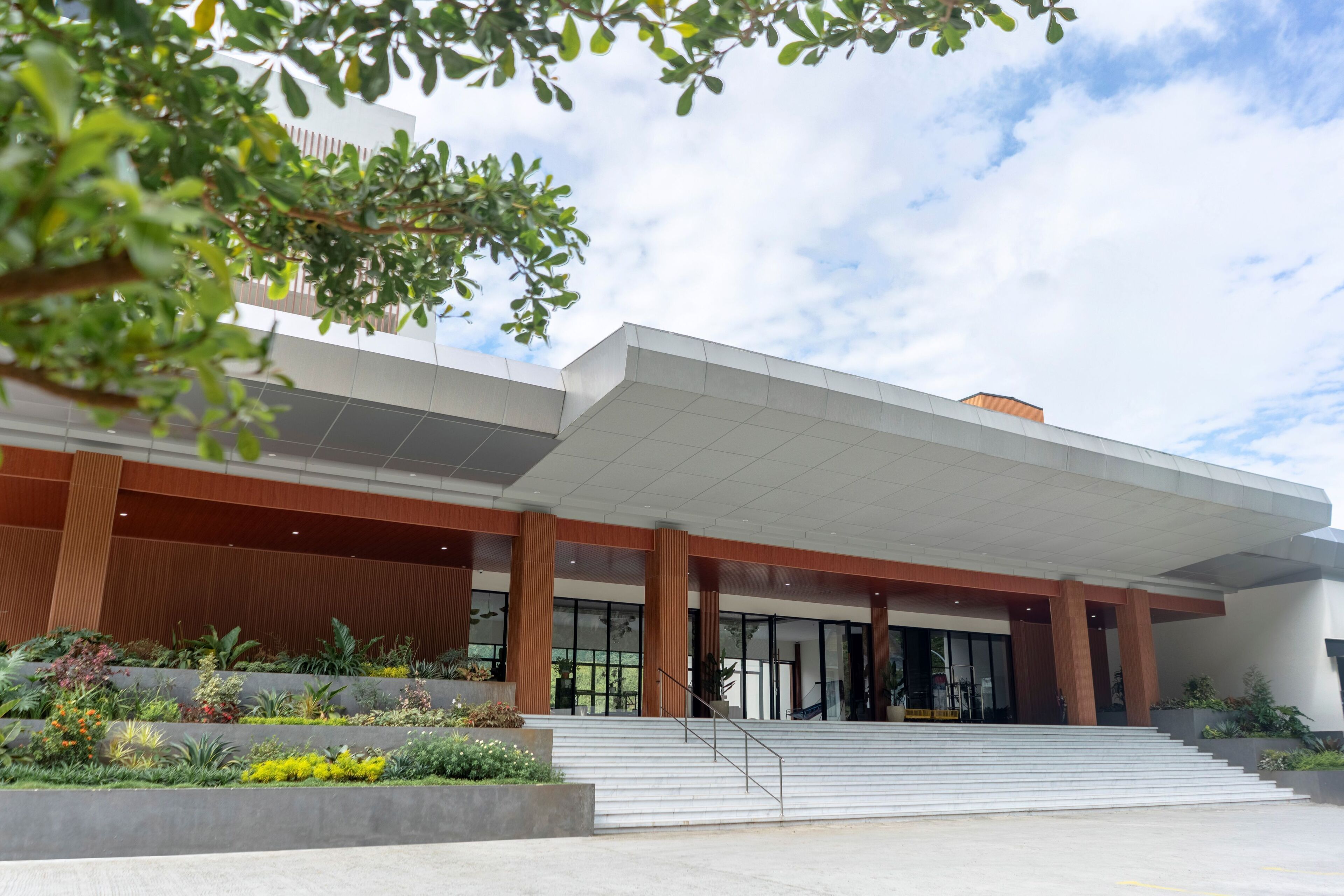 A modern building with a flat roof, large glass windows, and a staircase leading to the entrance.