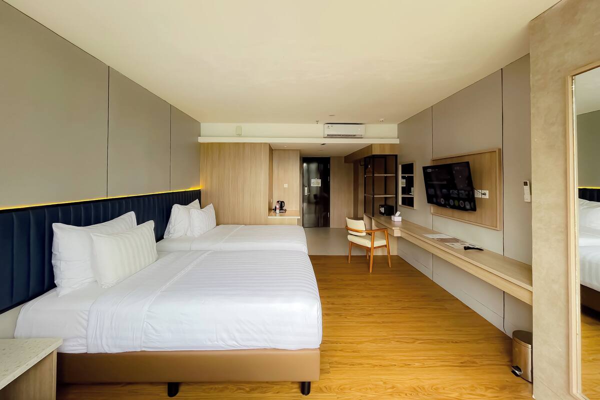 A modern hotel room with a large bed, a desk, a TV, and a wardrobe.