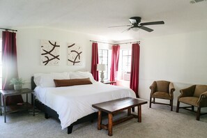 Een slaapkamer met een bed, twee stoelen, een tafel en kunst aan de muur.