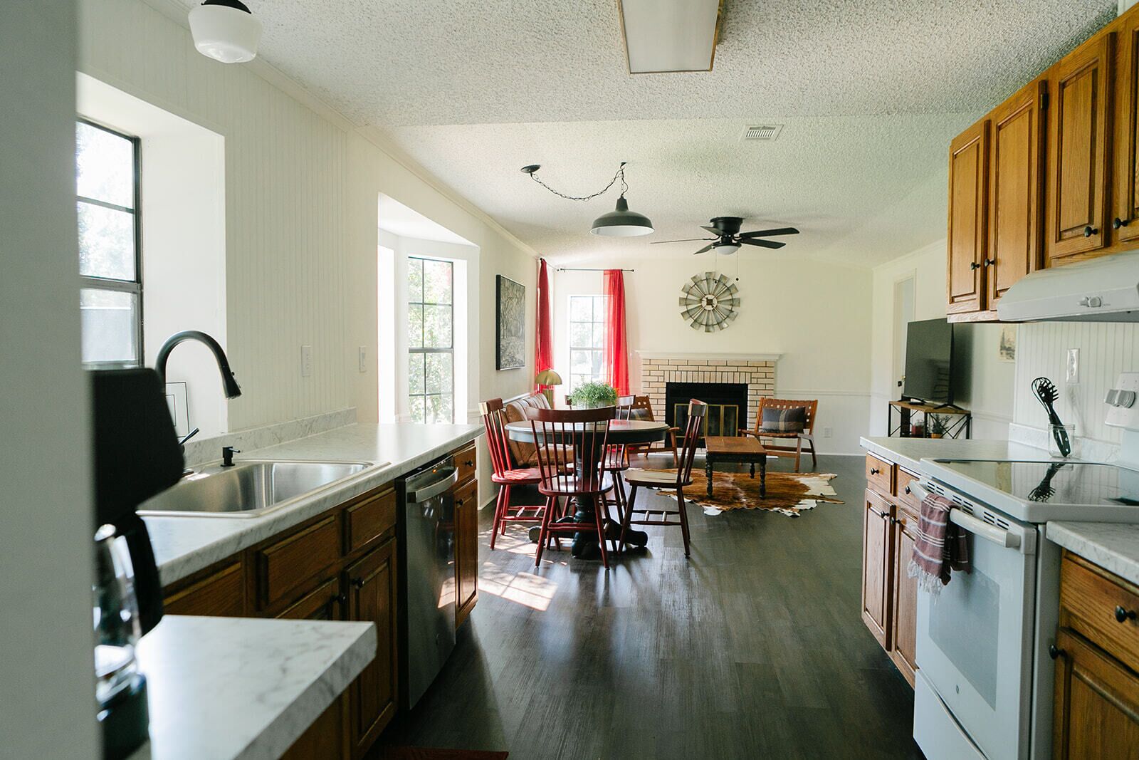 A spacious kitchen with wooden cabinets, a dining area with a fireplace, and a ceiling fan.