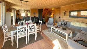 Interior acogedor de una cabaña con comedor, sofá y chimenea.