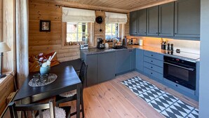 Una cocina compacta con paredes de madera, un área de comedor con una mesa y sillas, y una alfombra estampada.