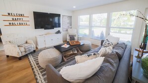 Una sala de estar moderna con un sofá, sillones, una mesa de centro y un televisor montado en la pared.