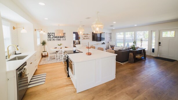 Una cocina moderna con una isla central, armarios blancos e iluminación colgante.