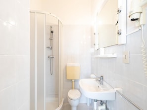 A modern bathroom with a glass-enclosed shower, a white toilet, and a sink with a mirror above it. - Experience Comfort in our Flat Near the Beach (Lignano Sabbiadoro)