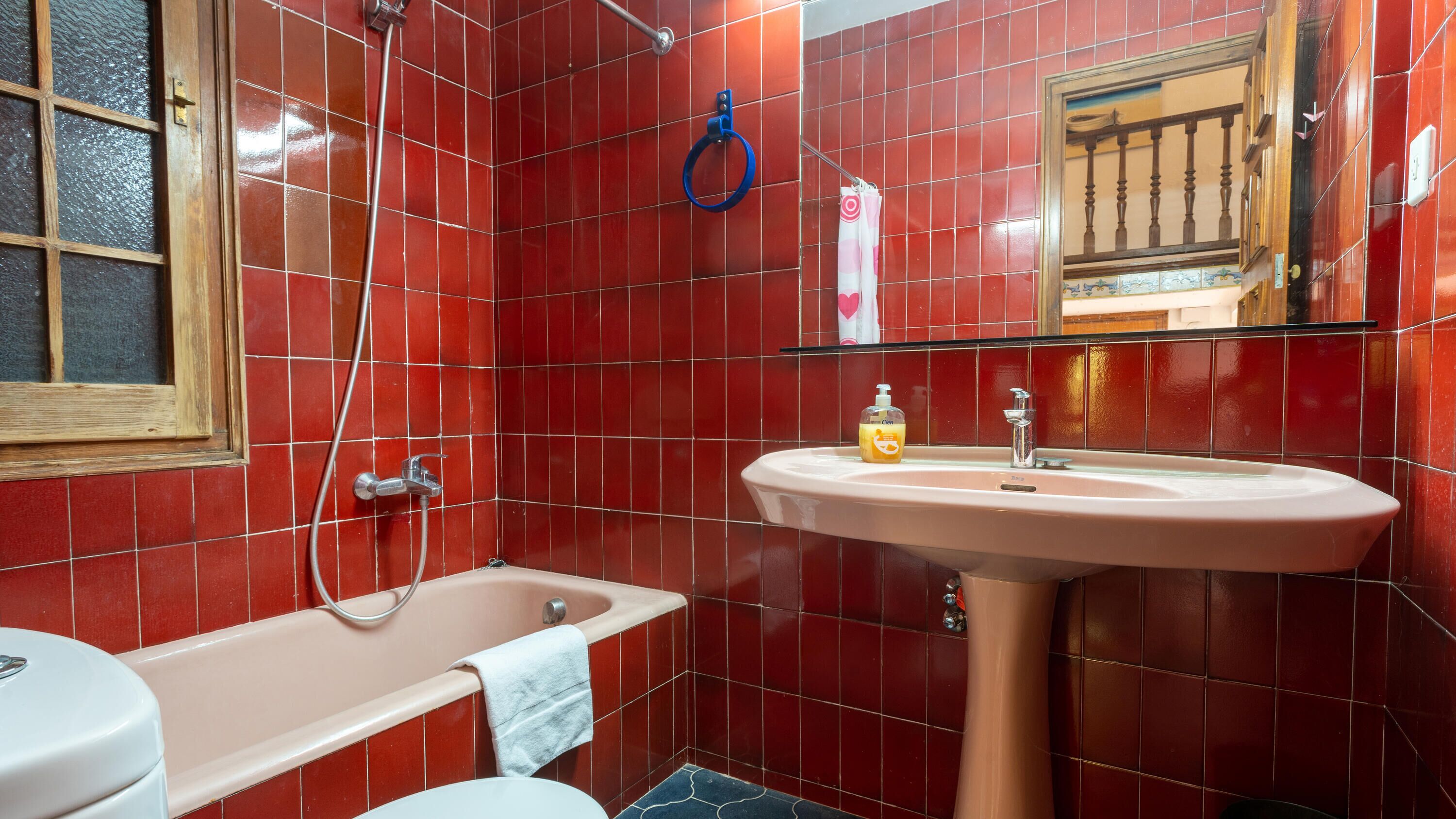Une salle de bain avec des carreaux rouges, une baignoire, un lavabo et un miroir.