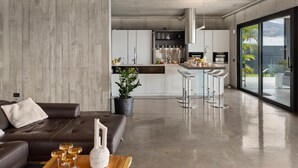 A modern kitchen with a central island, bar stools, and a dining area with a sofa and coffee table. - KARAT Villa Atelier de la Vega (Playa Paraiso)