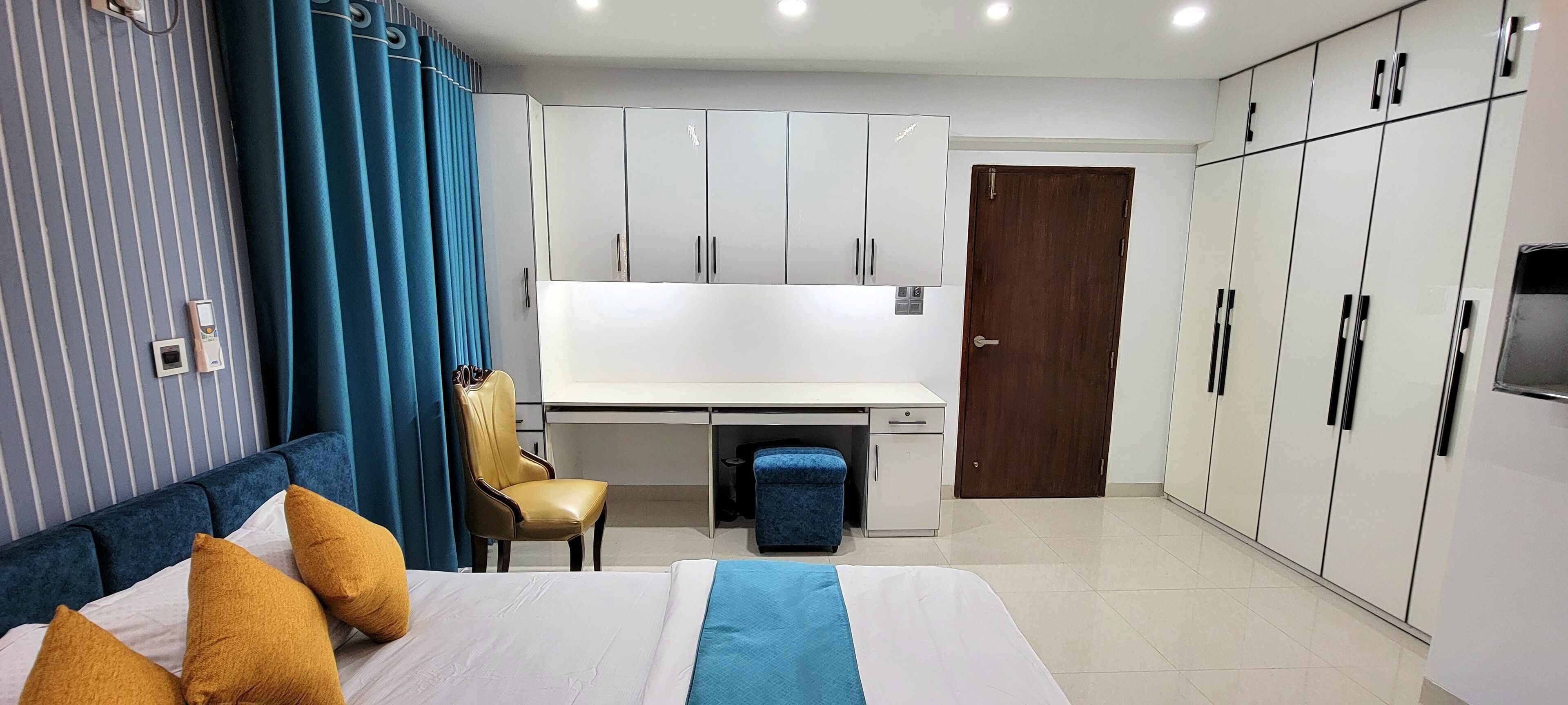 Une chambre d’hôtel avec un lit, un bureau, une armoire et une porte.