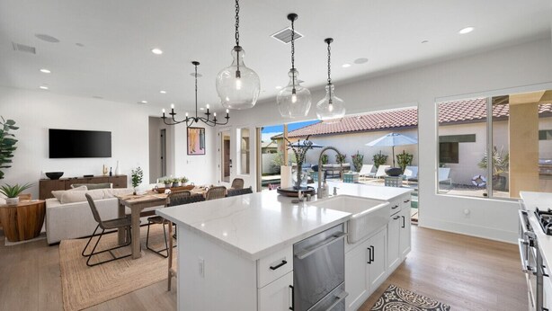 A spacious kitchen with a large island, modern pendant lights, and a view to a patio area. - Desert pool retreat w/ mountain views (La Quinta)