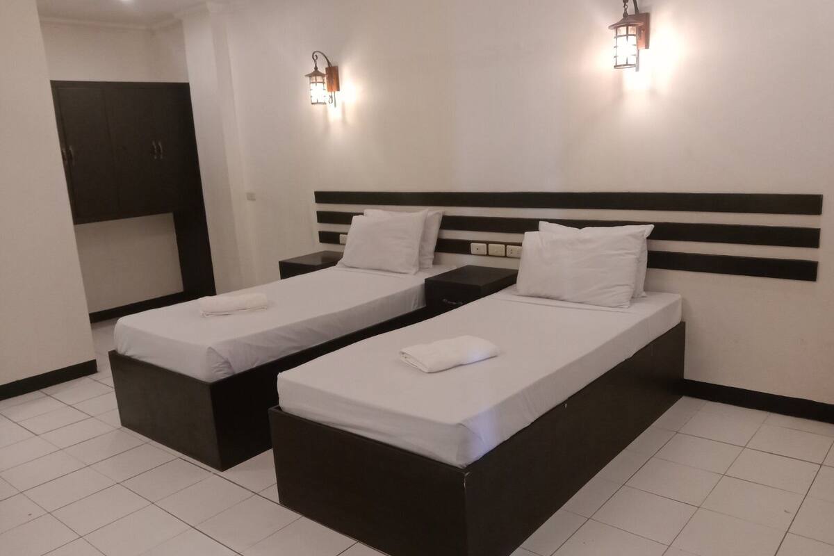 Una habitación de hotel con dos camas individuales, un escritorio pequeño y un armario.